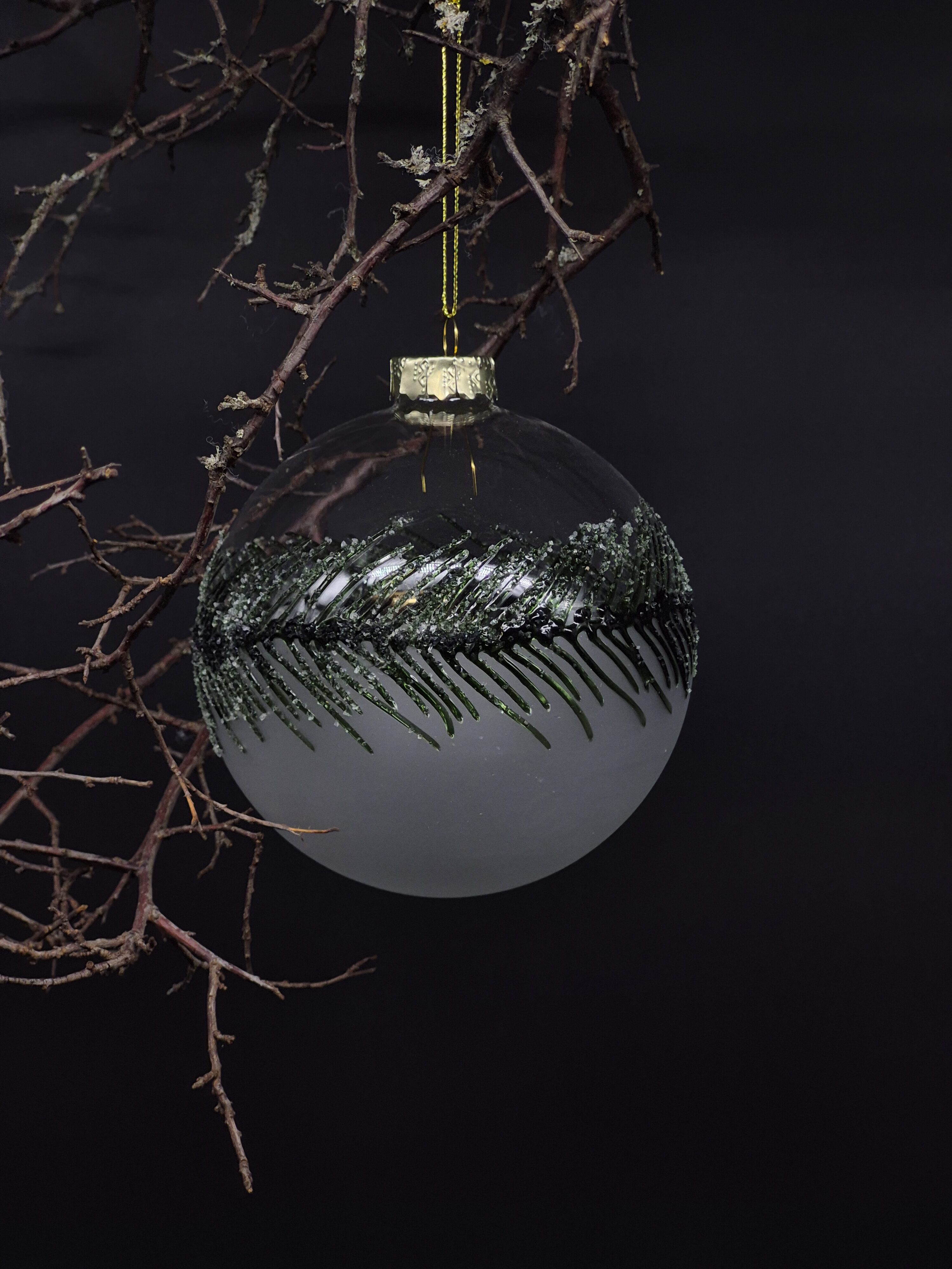 Edle Christbaumkugel aus Glas mit tannengrüner Dekoration.