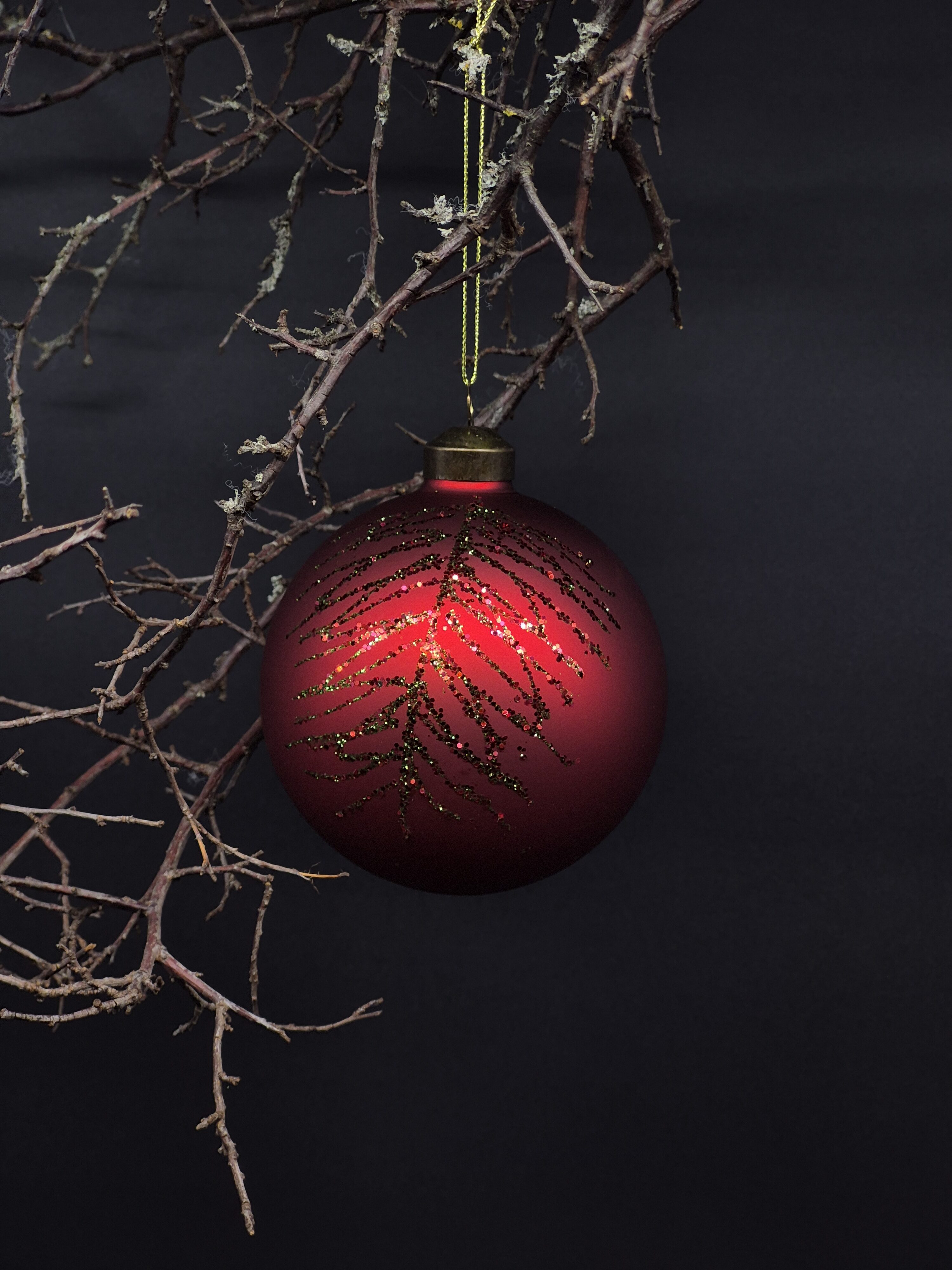 Klassische Christbaumkugel aus Glas in Rot mit glitzerndem Muster.